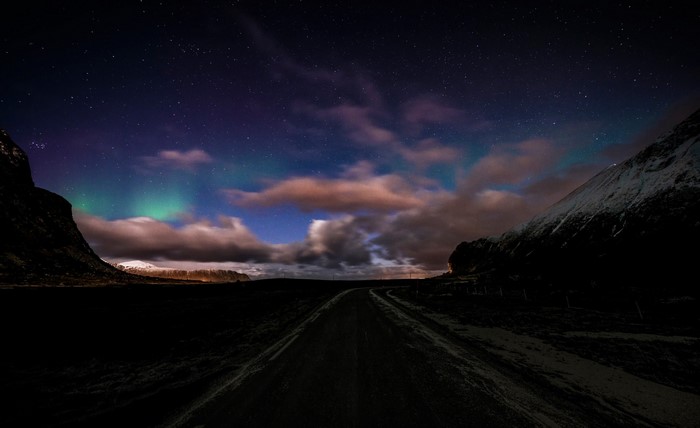 Aurora Borealis over a road between mountains at night