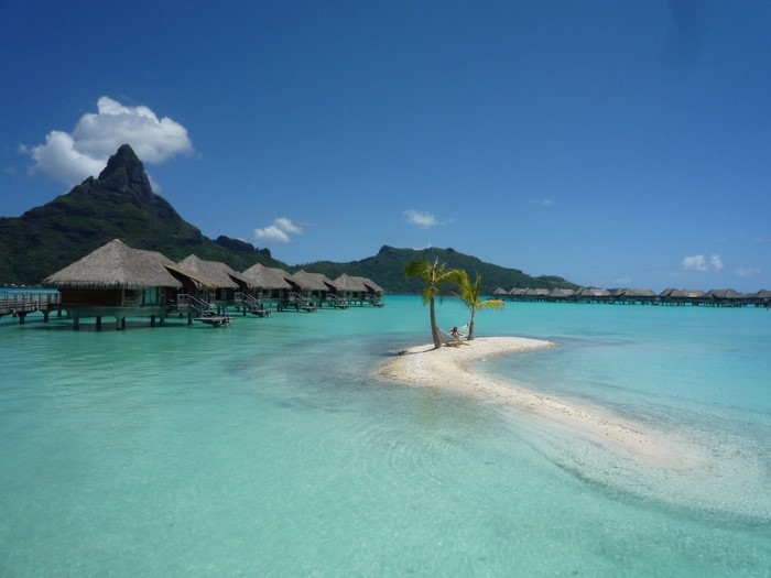 Overwater bungalows on a tropical island with a mountain backdrop