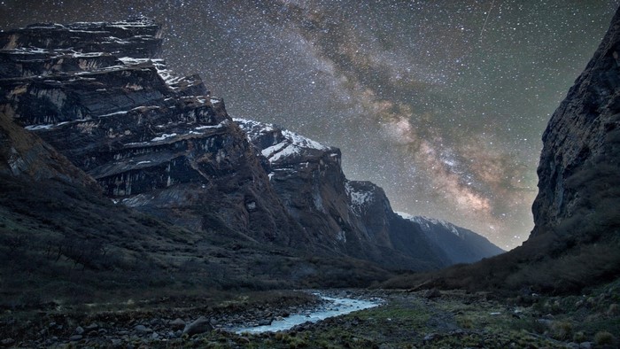 Milky Way over rocky mountains and river at night