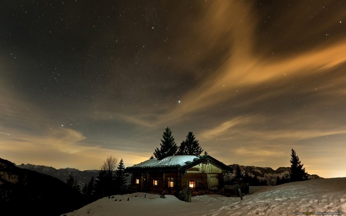 Wooden cabin under starry night sky in winter