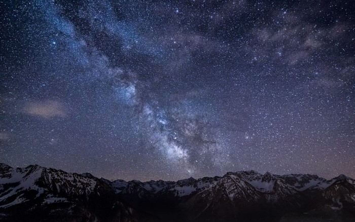 Milky Way galaxy over snow-capped mountains at night