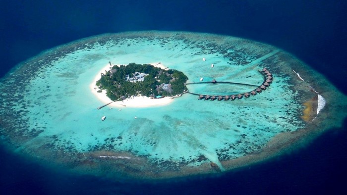 Aerial view of a tropical island resort with overwater bungalows