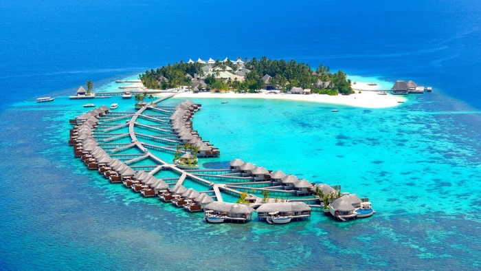 Aerial view of a tropical island resort with overwater bungalows