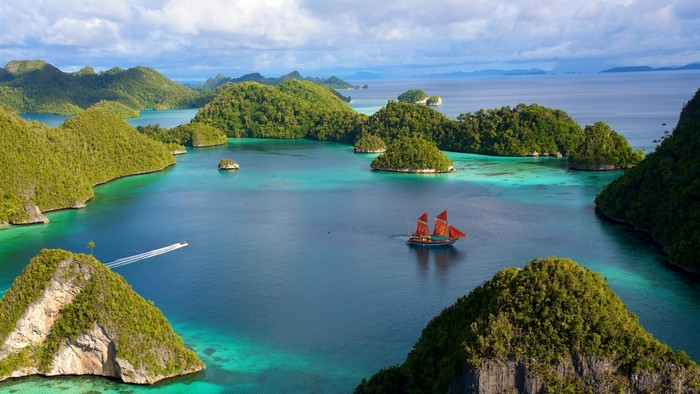 Tropical archipelago with islands, turquoise water, and a sailboat