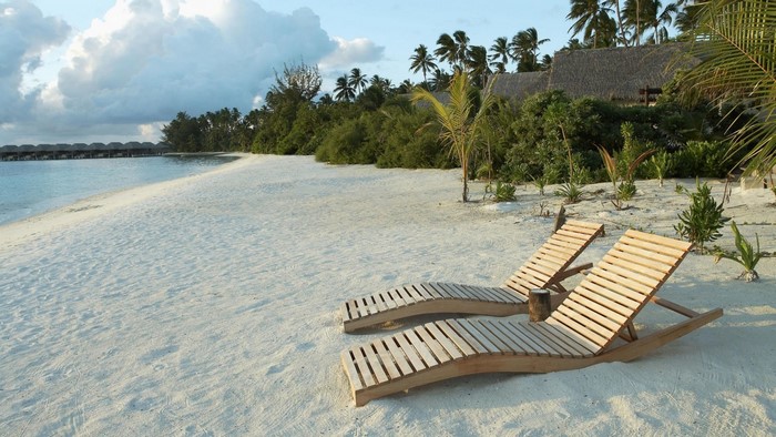 Beach resort with lounge chairs and overwater bungalows