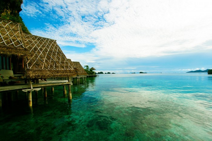 Overwater bungalows on a tropical island with clear turquoise water