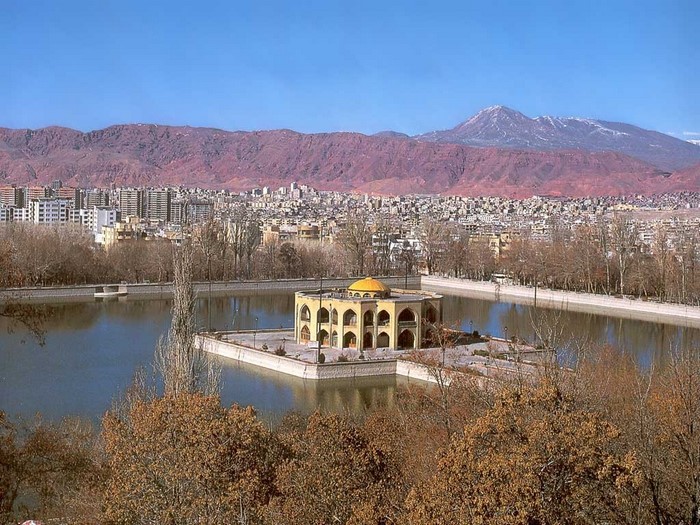 Palace in a lake with city and mountains in background