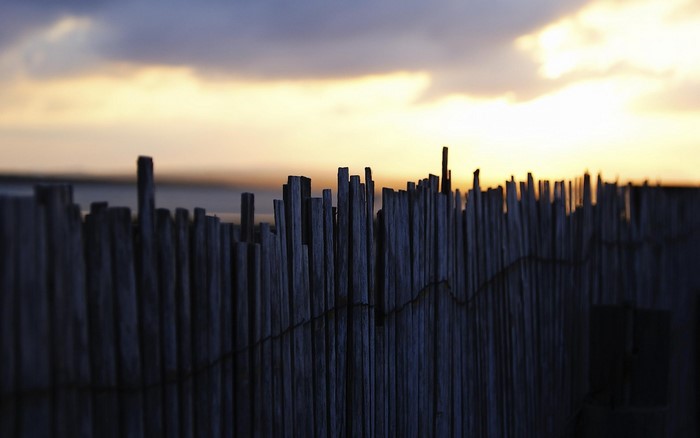 Wooden fence at sunset with clouds over the horizon