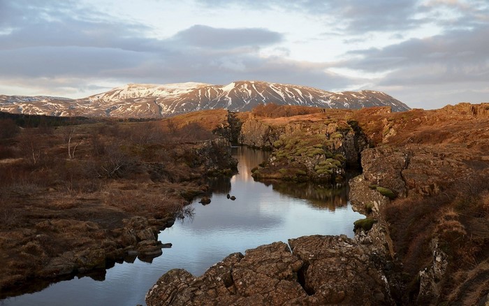A rift valley with a river and snow-capped mountains