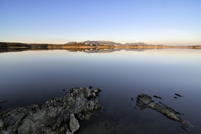 Calm lake with distant mountains and rocky shore