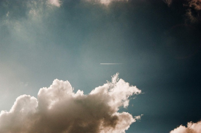 Airplane contrail in a cloudy sky