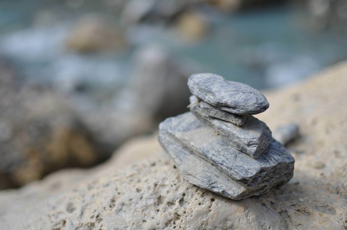 Stack of stones on a rocky shore with blurred water background