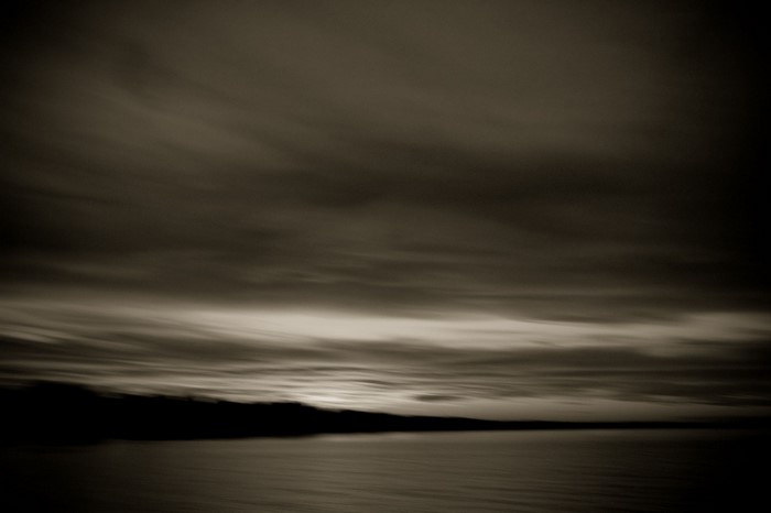 Monochrome seascape with silhouetted land and cloudy sky