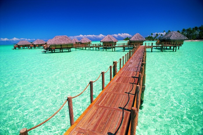 Overwater bungalows on a turquoise lagoon with a wooden pier