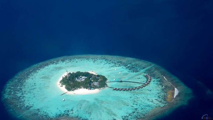Aerial view of a tropical island with overwater bungalows