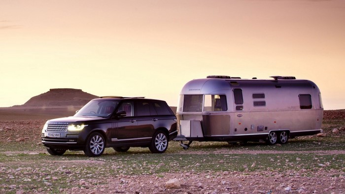 Range Rover towing an Airstream trailer in a desert landscape