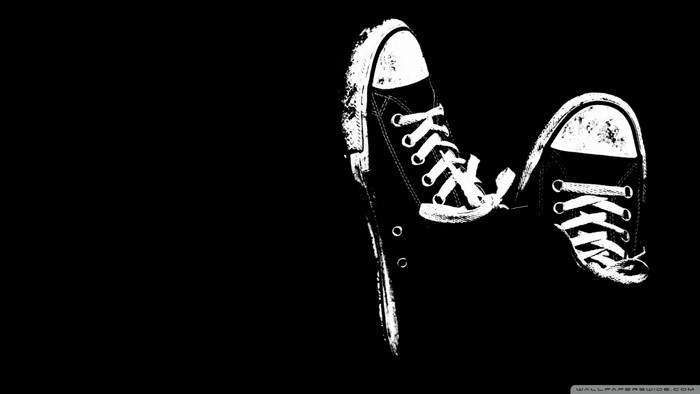 Black and white Converse shoes on black background