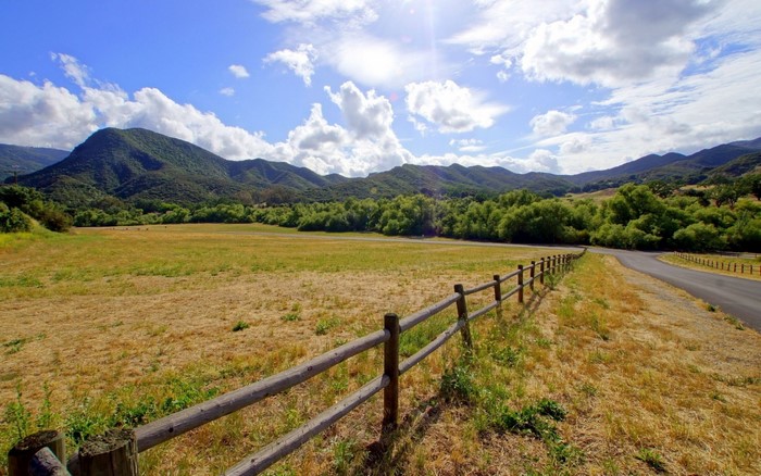 Rural landscape with mountains, fields, and a wooden fence