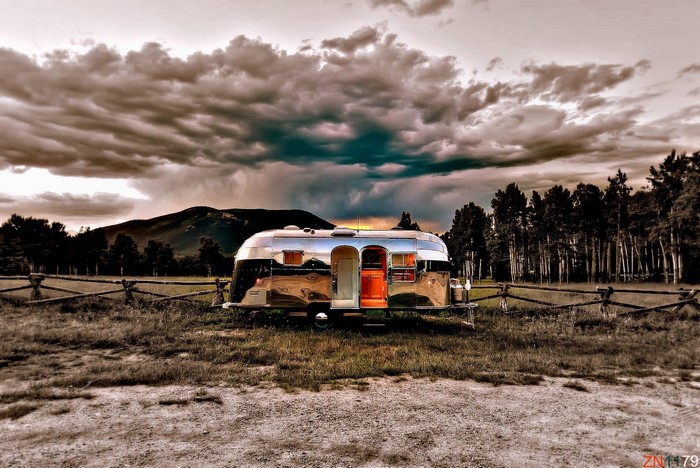 Airstream trailer in a rural landscape with mountains and trees