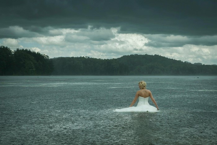 Woman in wedding dress in lake during rain