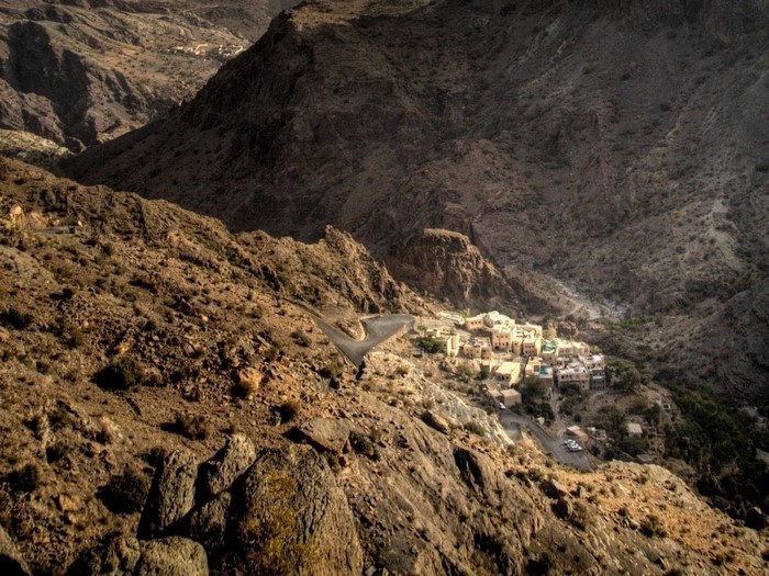 Village nestled in a rocky mountain valley with a winding road