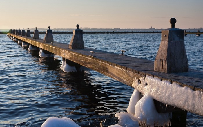Wooden pier with ice formations on a calm body of water