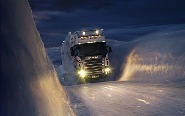 Scania truck driving on a snowy road at night