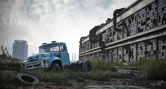Abandoned truck and factory in overgrown industrial area