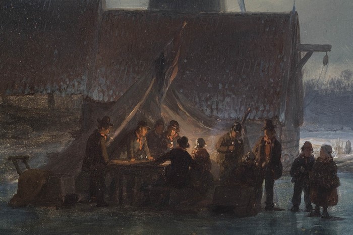 People gathered around a table under a tent in winter