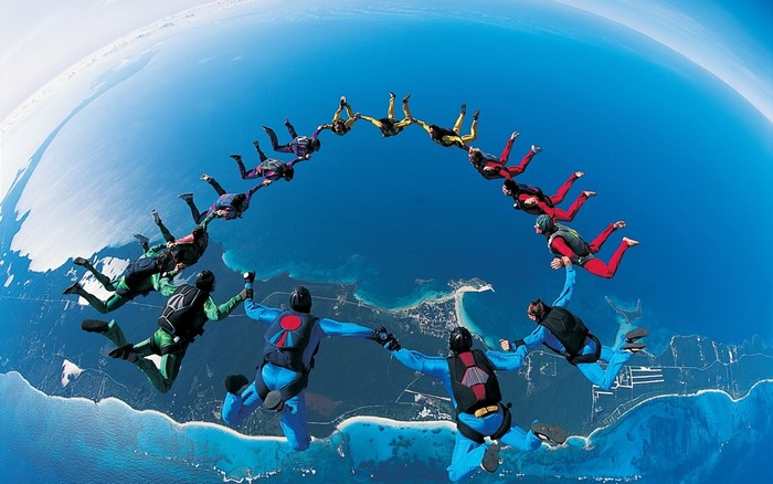 Skydivers form a circle in the sky over an island