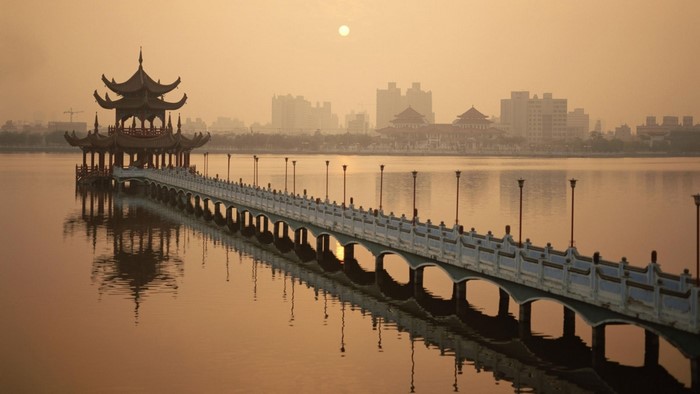 Pagoda bridge over water at sunset with cityscape