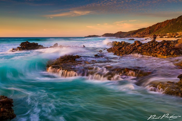 Ocean waves crashing on rocky shore at sunset