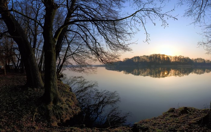 Sunset over a calm lake with trees on the shore