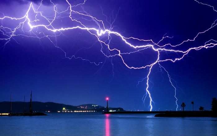 Lightning strikes over a body of water at night