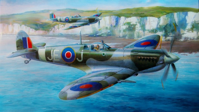 Two Supermarine Spitfires fly over the sea near white cliffs