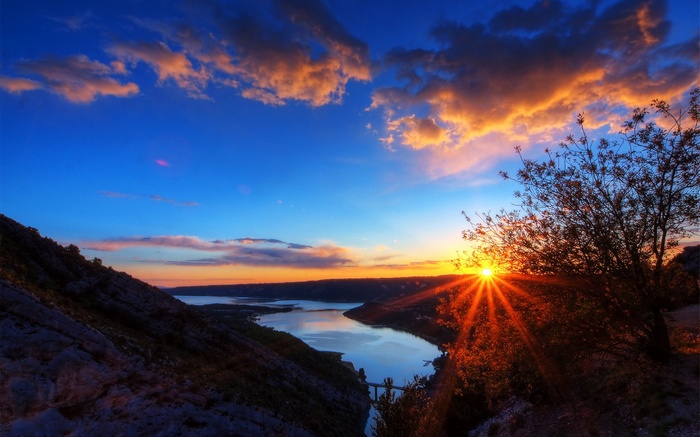 Sunset over a river valley with mountains and clouds