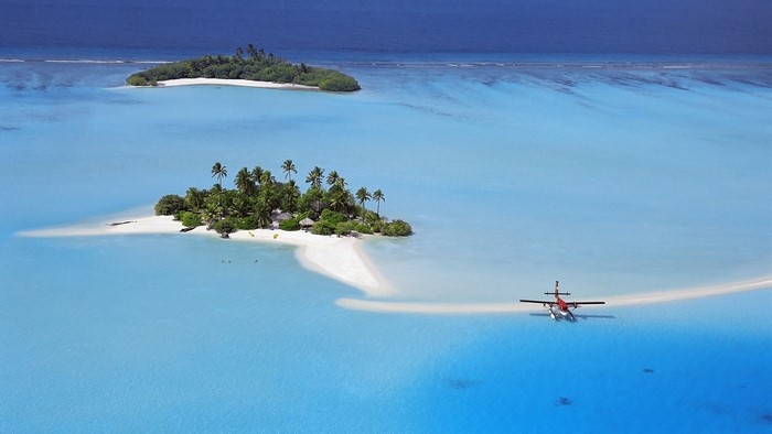 Seaplane lands in a tropical lagoon near islands