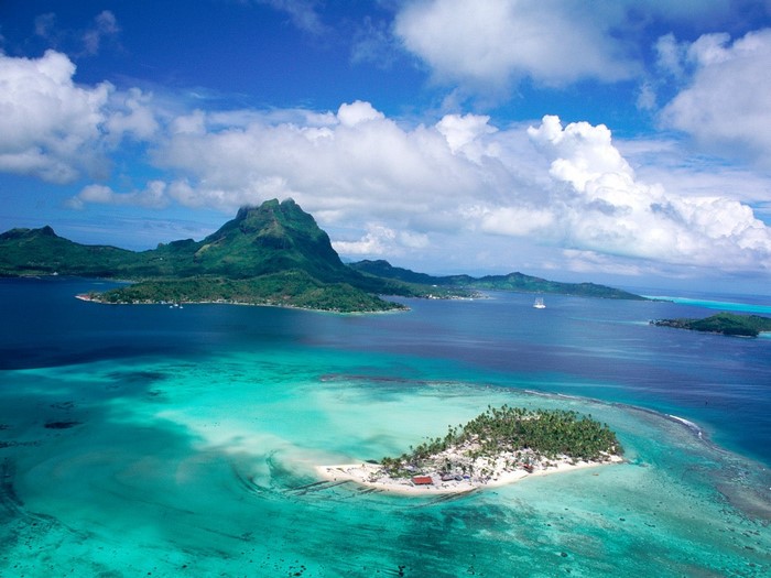 Aerial view of a tropical island lagoon with mountains in the background