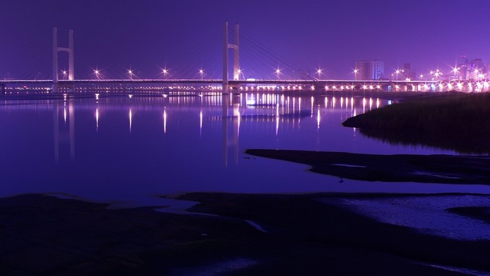 Bridge over water at night with city lights