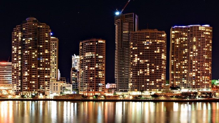Cityscape at night with illuminated skyscrapers and water reflections