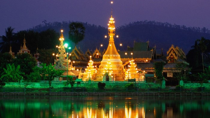 Golden pagoda illuminated at night by a lake