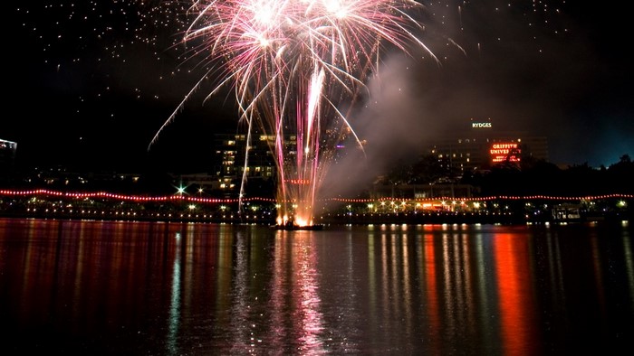 Fireworks over a city skyline reflected in water