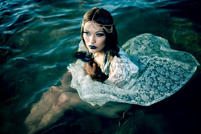 Woman in white lace dress submerged in water