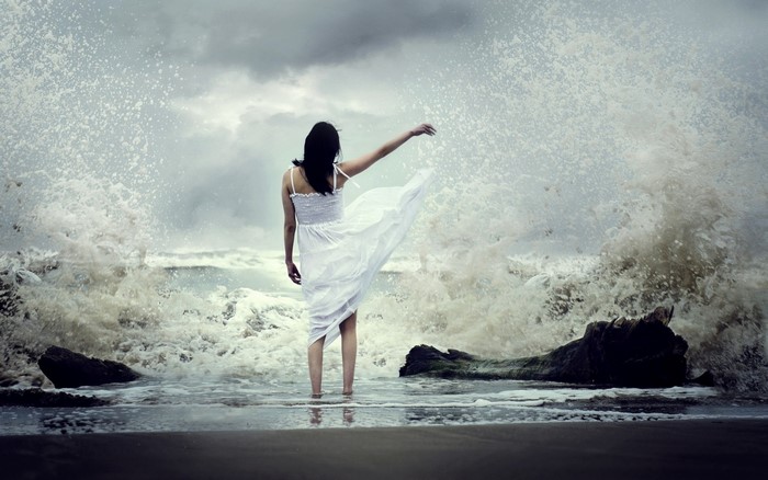 Woman in white dress standing in ocean waves