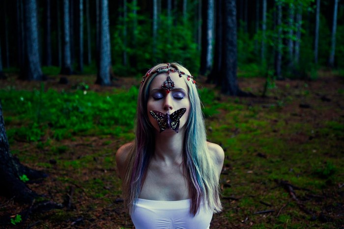 Woman with butterflies in a dark forest