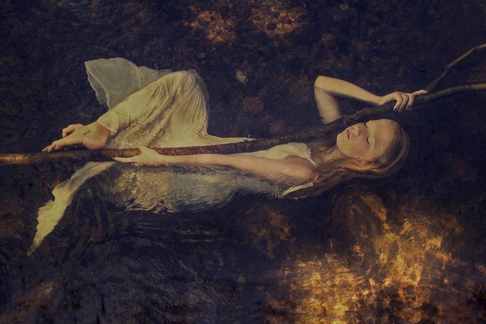 Woman floating in water holding a branch