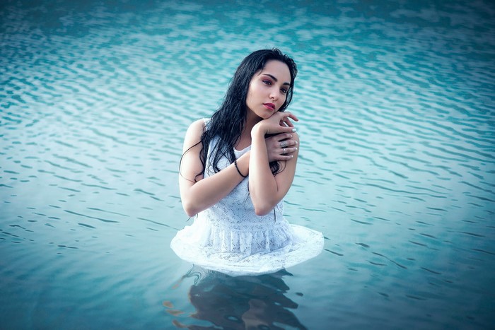 Woman in white dress standing in blue water