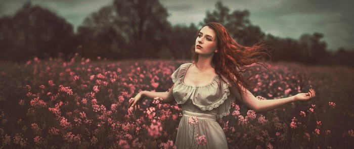 Redhead woman in a field of pink flowers