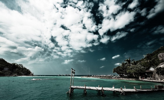 Wooden pier on a tropical bay with boats and islands
