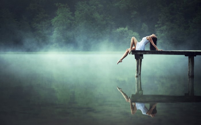 Woman in white dress on a pier in the mist